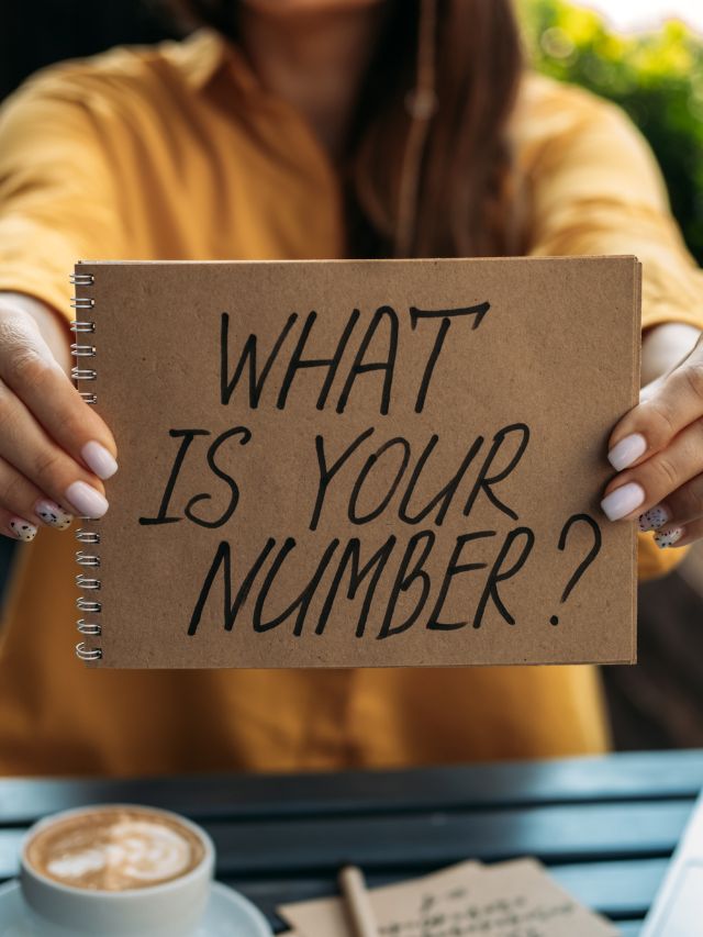 girl holding up notebook with what is your numerology number? written on it