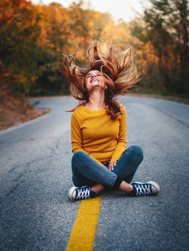girl filled with happiness sitting in the middle of the road