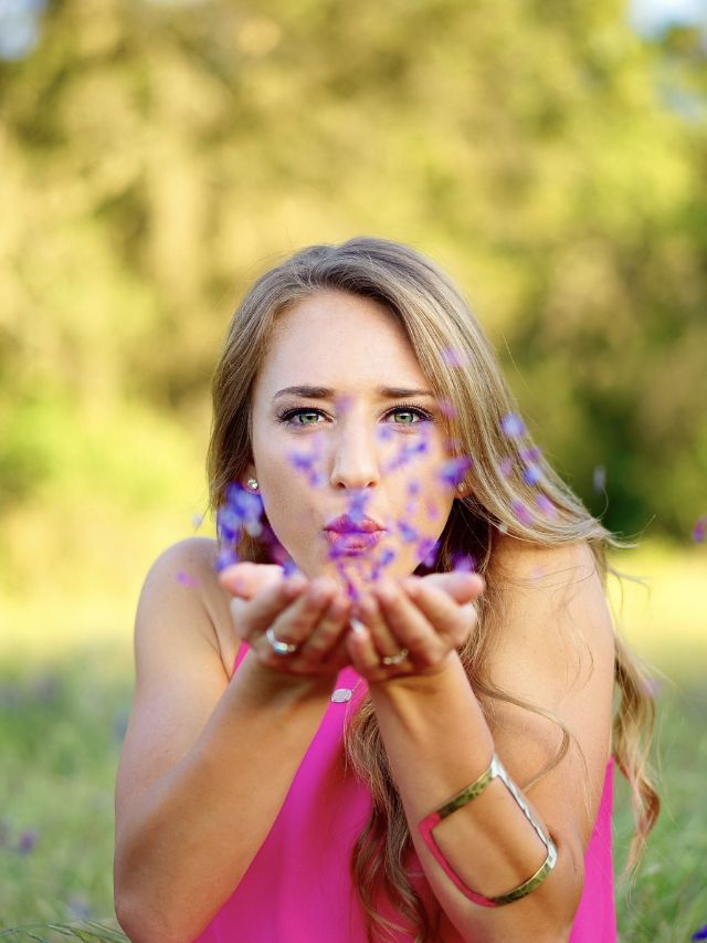 girl blowing purple flowers