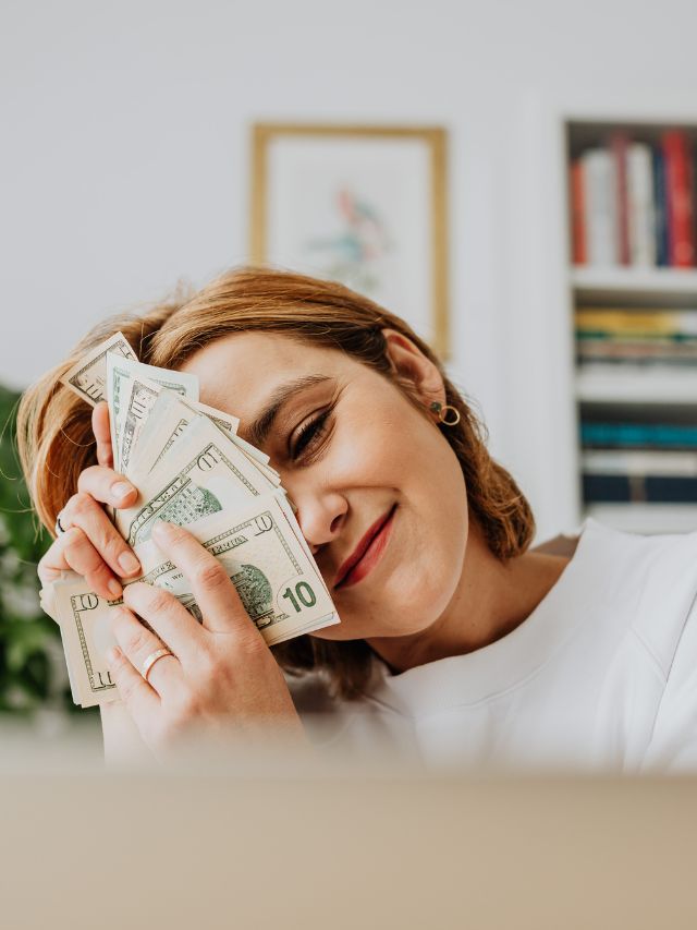 happy woman holding money in office