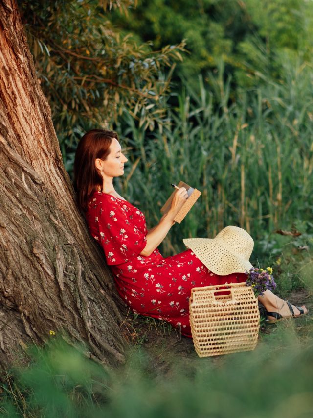 woman reading a book by a tree
