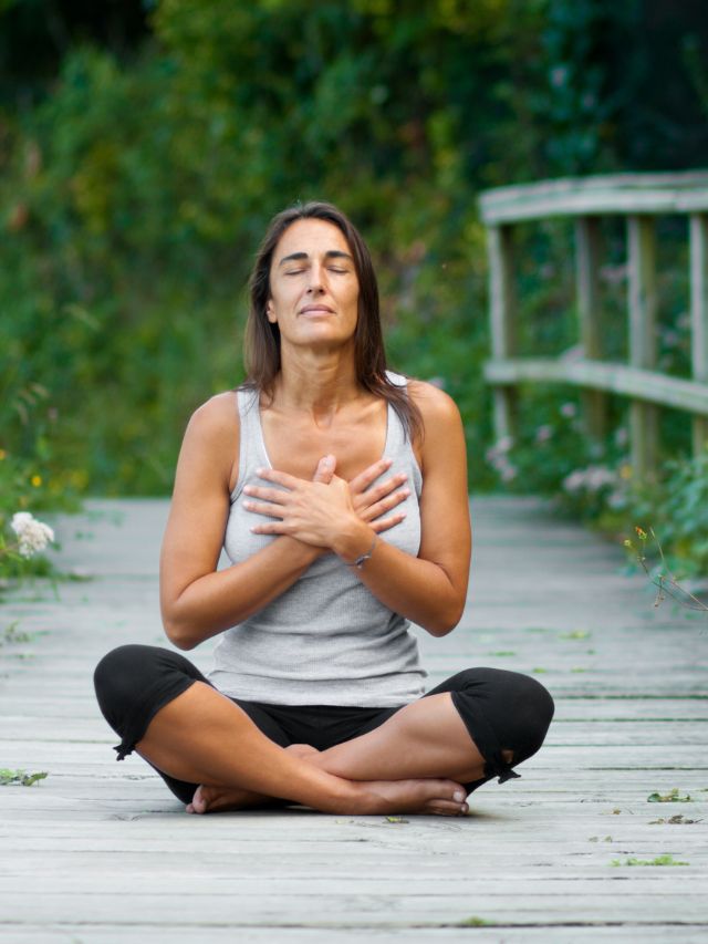 woman meditating in lotus position on board walk