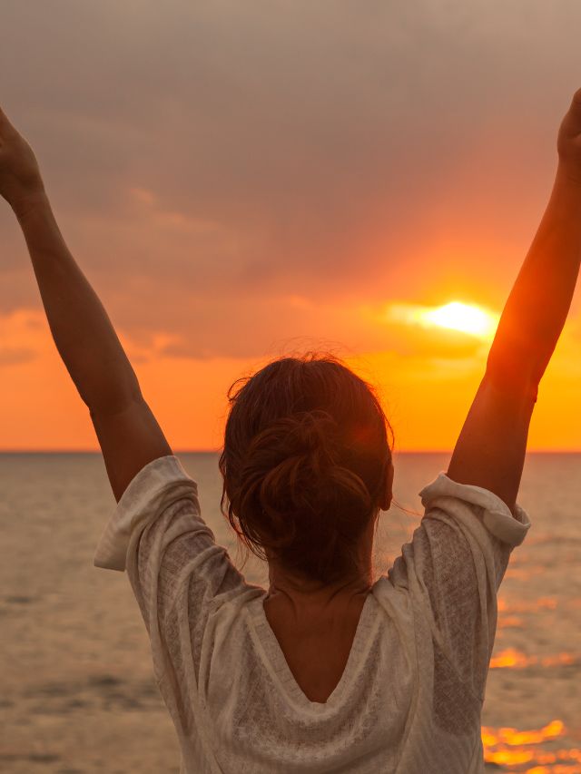 happy woman with arms up on the beach 