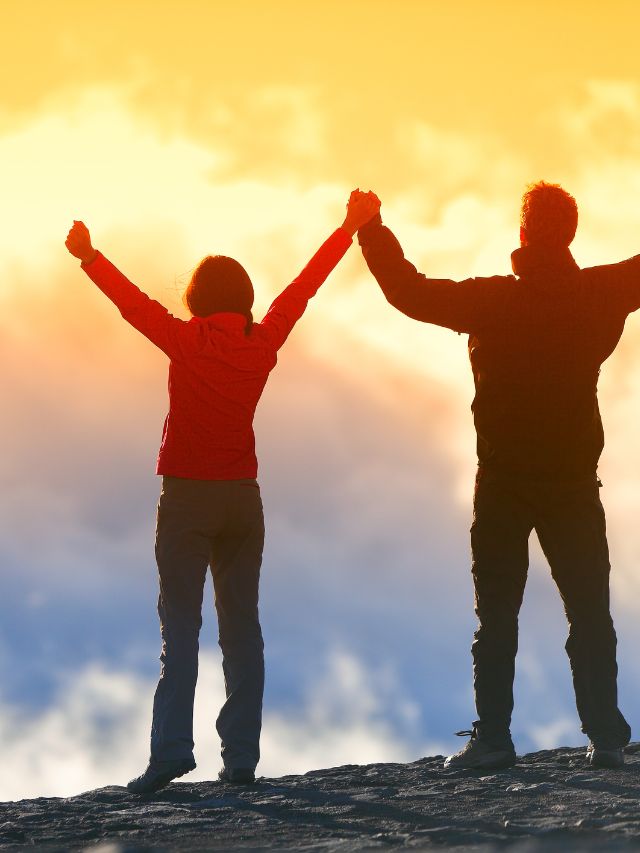 man and woman holding hands raised in the air