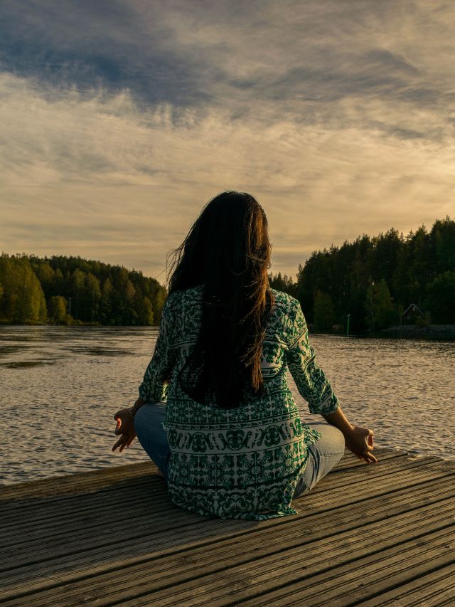 a girl meditating on a dock near water