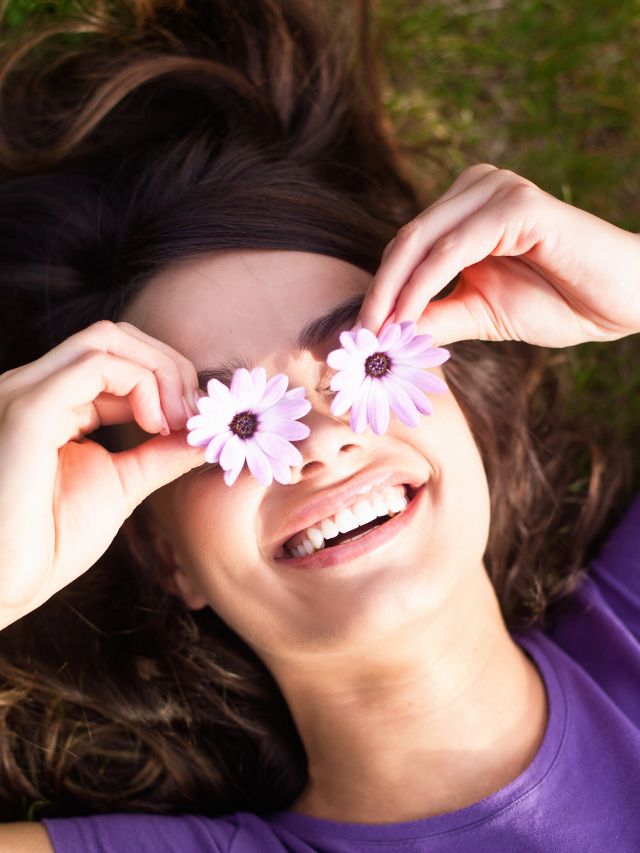 girl smiling with flowers instead of sunglasses