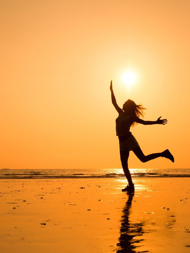 woman jumping at sunset on beach