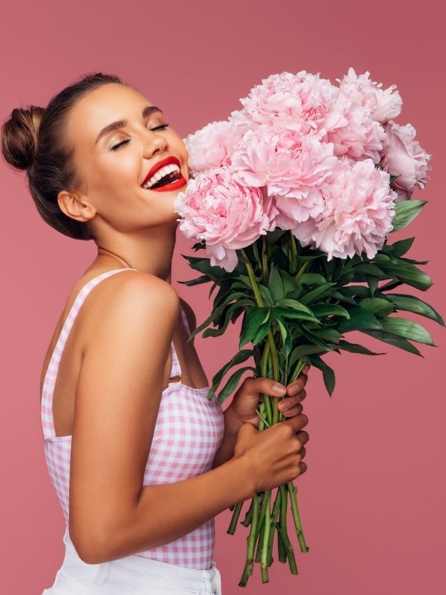 happy woman holding a bouquet of pink flowers