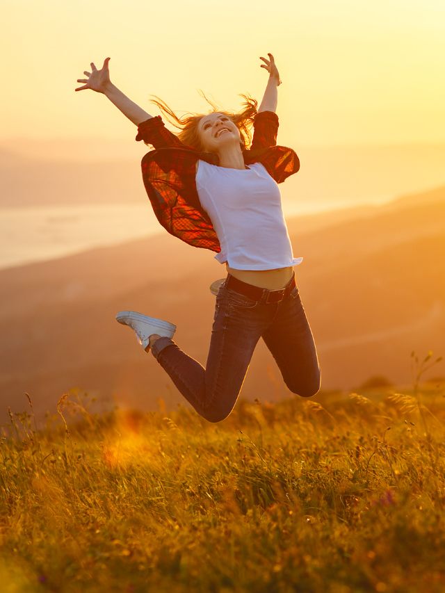 happy woman jumping and enjoying life at sunset in the mountains