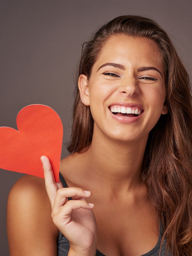 young woman holding a blank red heart smiling