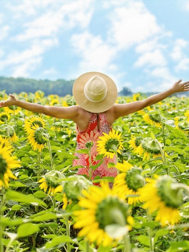 a girl in a meadow of flowers with her arms up in the air