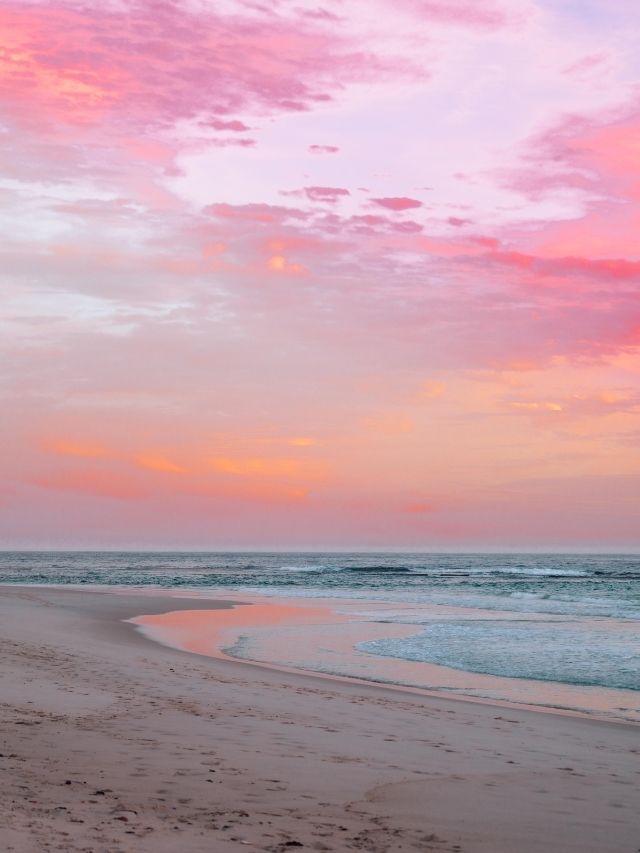 beach with pink and orange sunset and blue water