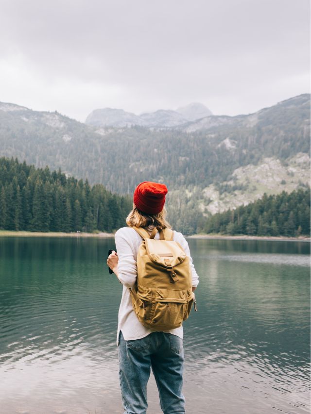 backpacker looking at mountain lake