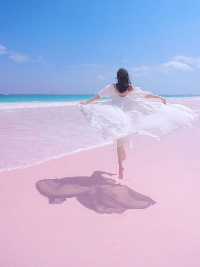 girl jumping on pink sand beach