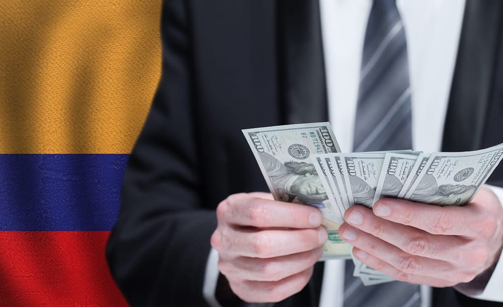 Hands holding dollar money on flag of Colombia