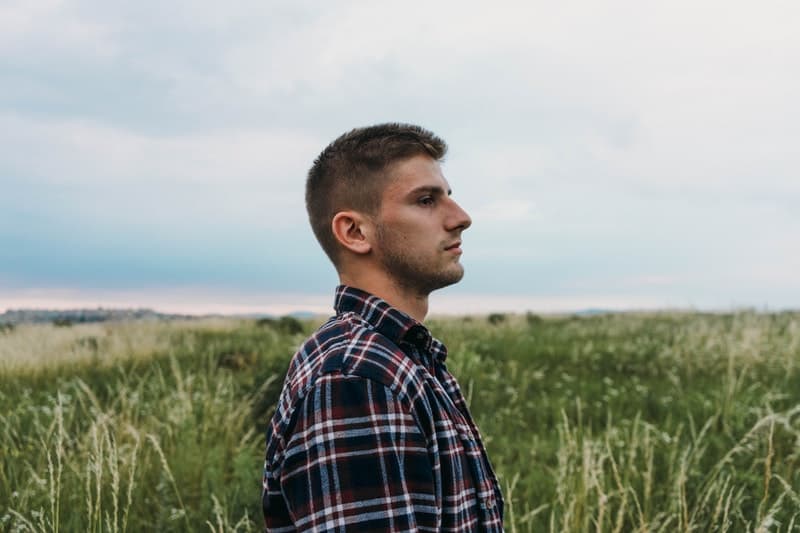 man standing in a grassfield on a sideview