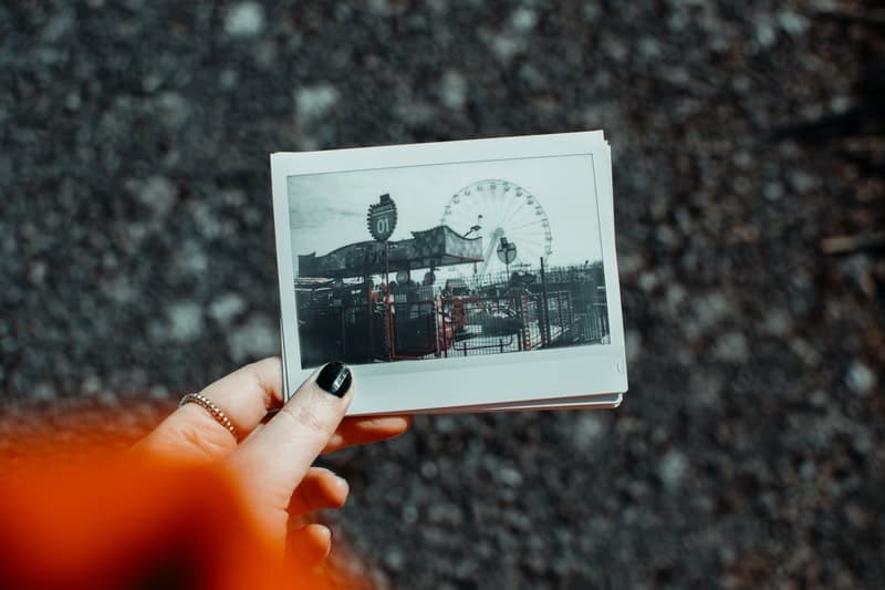 woman holding polaroid picture of an amusement park
