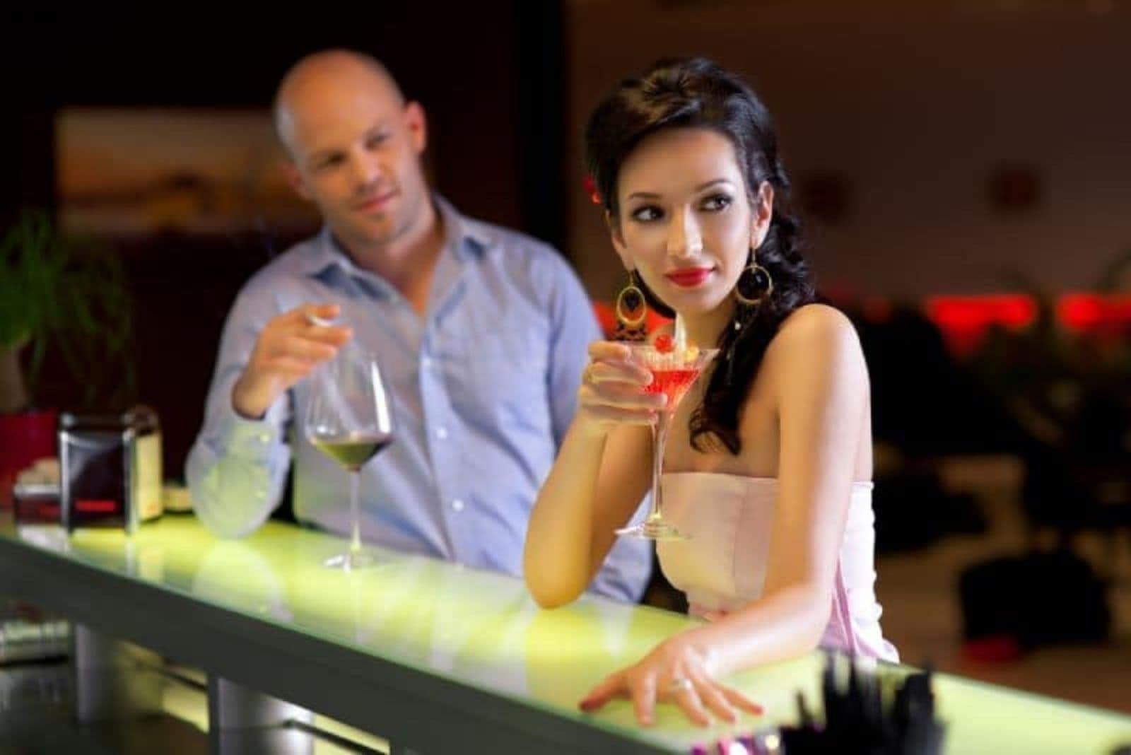a man drinks wine and looks at a woman