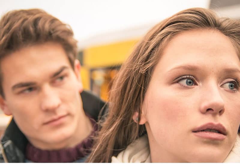 woman with teary eye and a man behind her