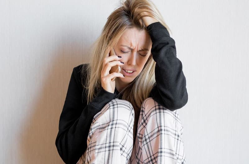 woman crying on phone sitting on the floor