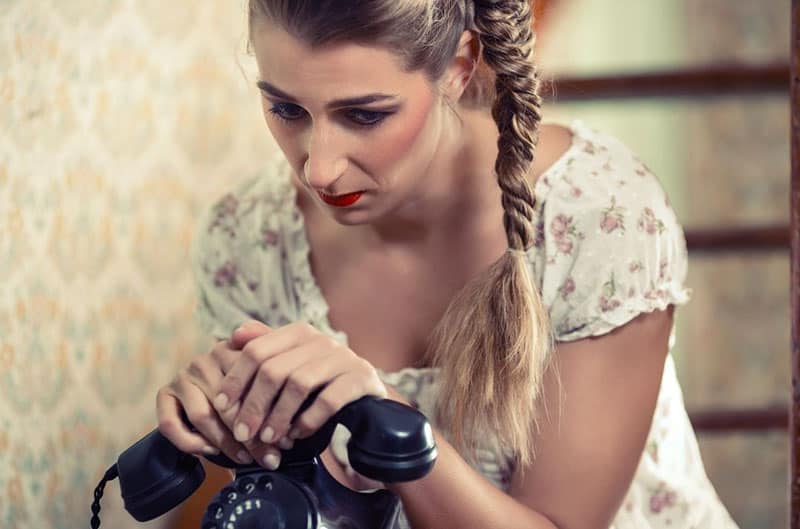 woman holding an old phone with braided hair in flower dress