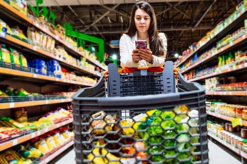 woman in grocery looking at her smartphone