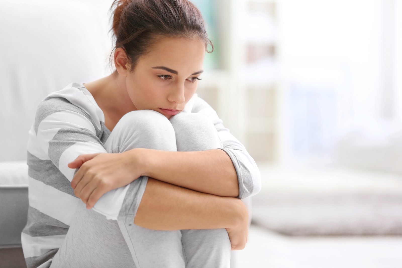 sad mindful woman sitting alone on the couch