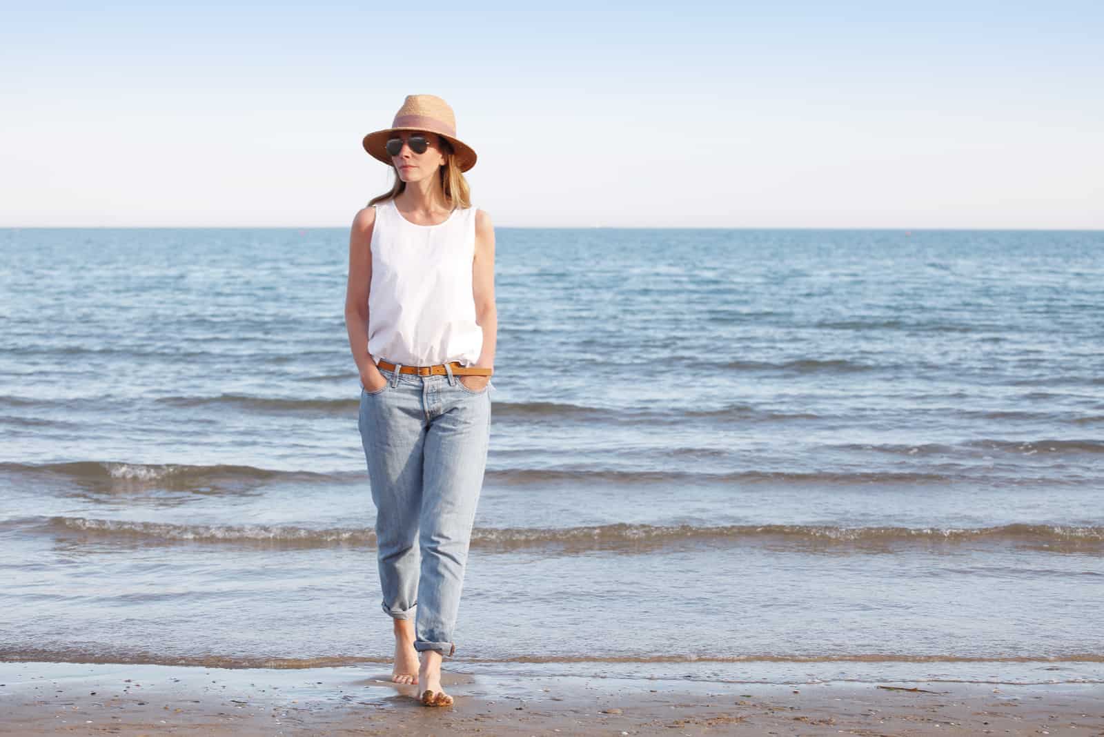 a woman with a hat on her head sets the beach