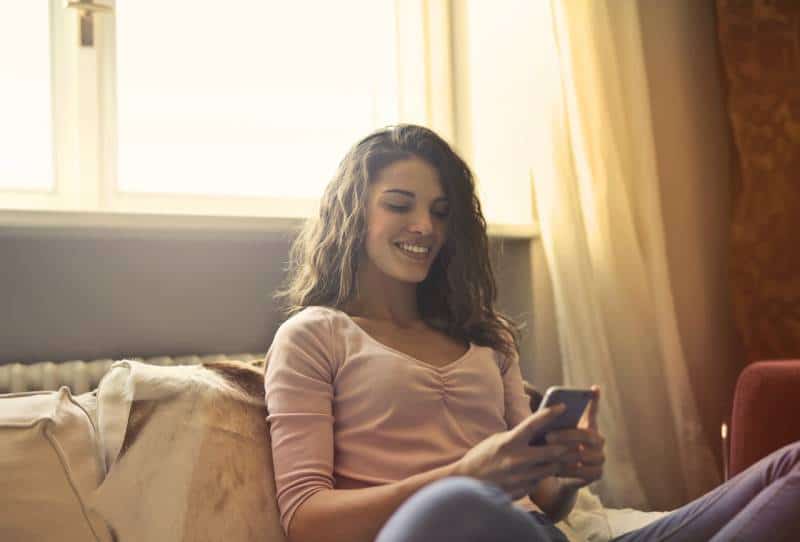 smiling girl typing her phone at home