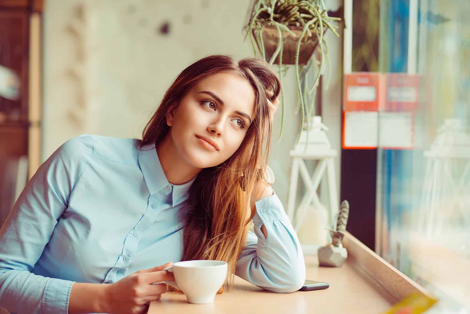 an imaginary brown-haired woman sits and drinks coffee