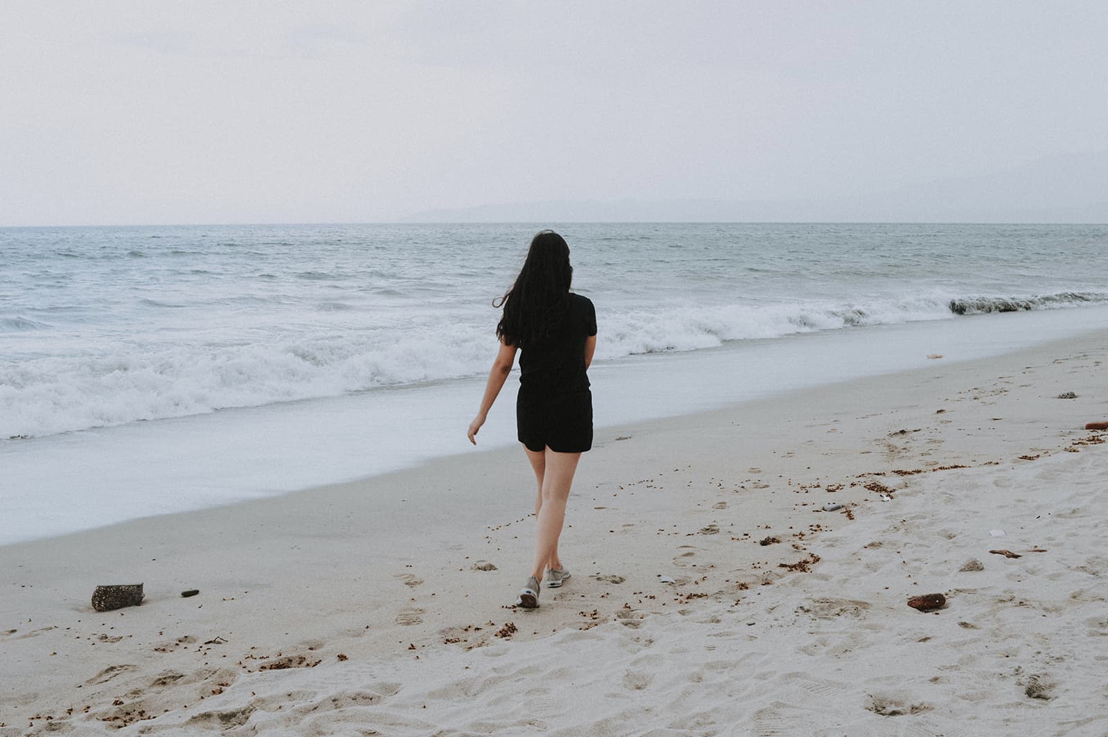 woman walking on the beach alone during daytime