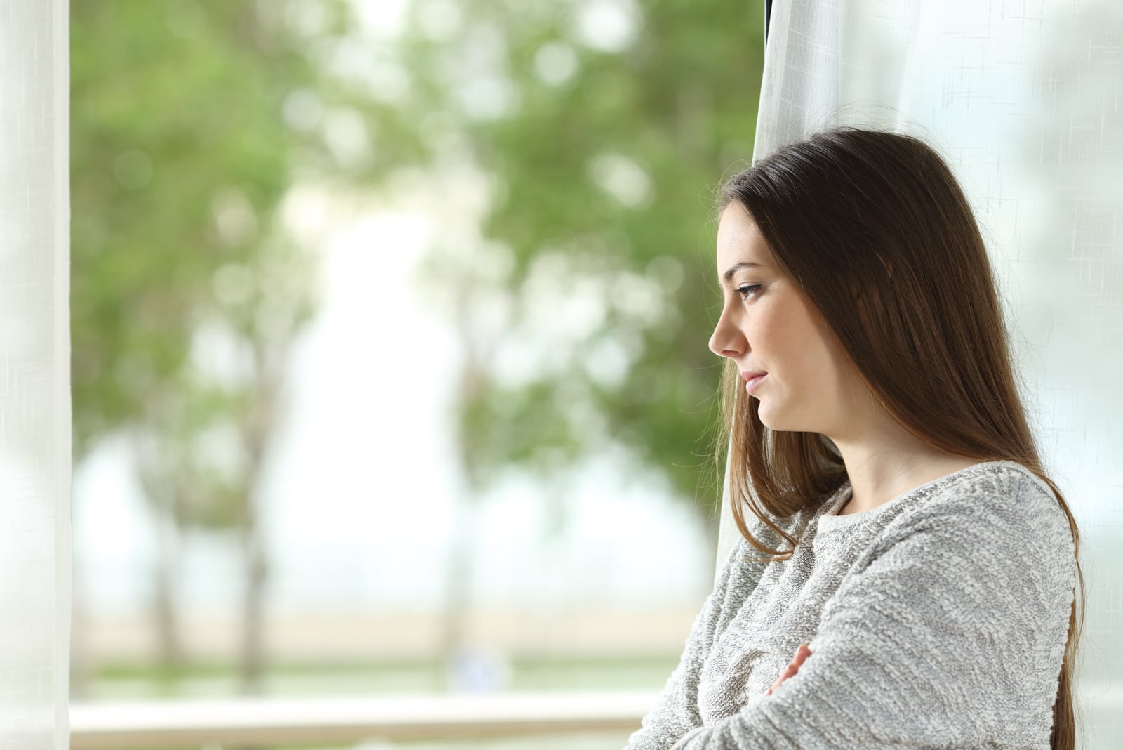 sad woman looking through window