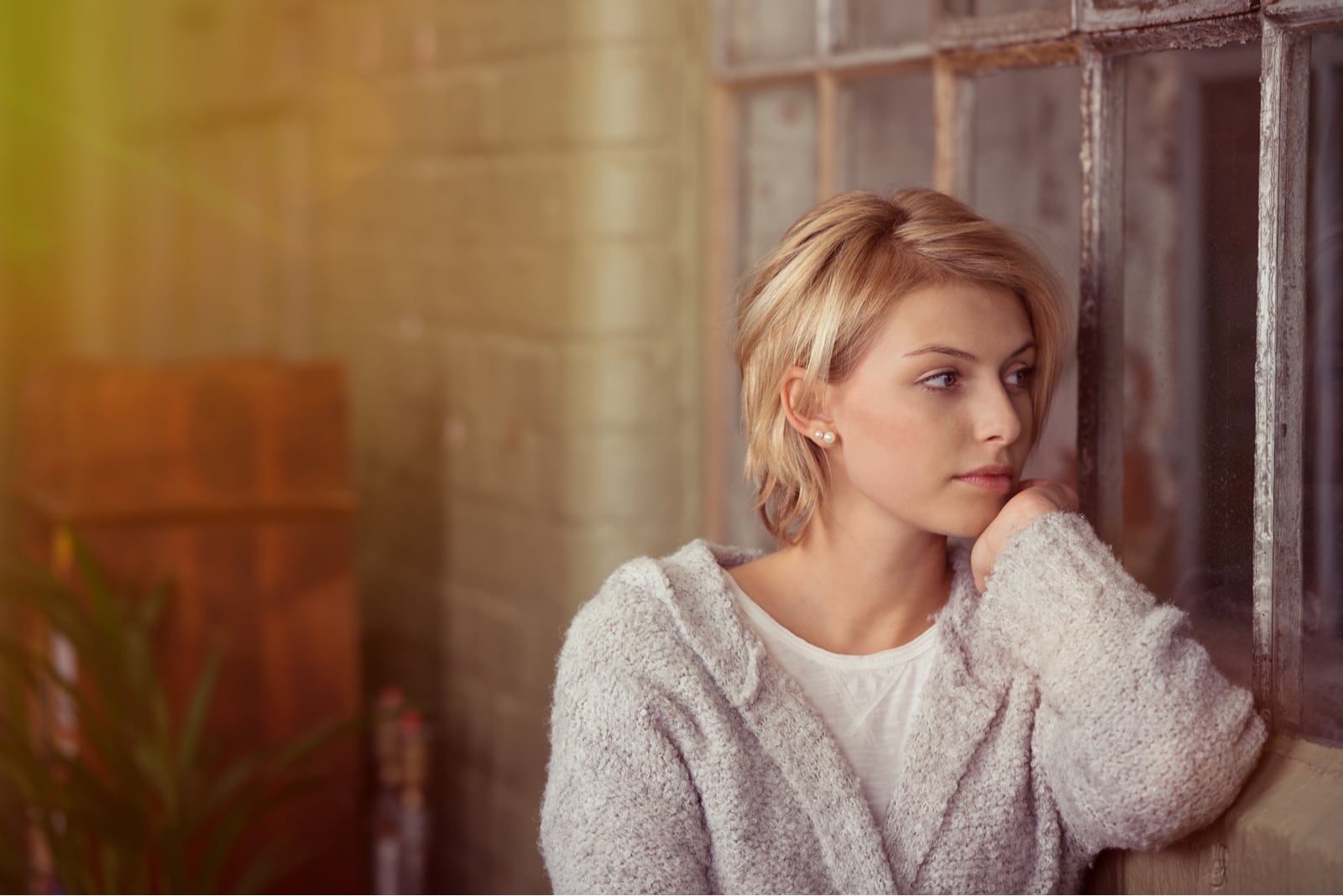 blond young woman sitting by the window