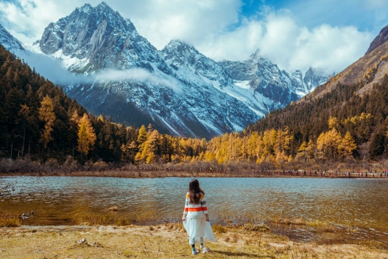 woman standing near lake looking at mountain