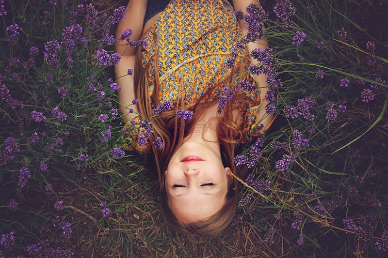 woman in yellow top sleeping beside lavenders