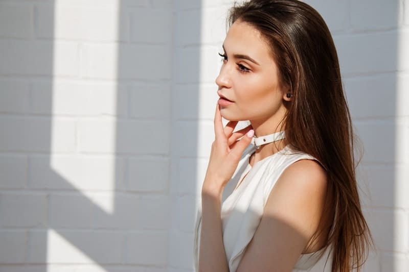 woman thinking in white top near a white wall