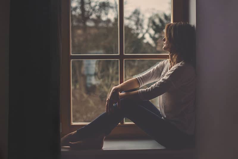 young sad woman sitting next to window