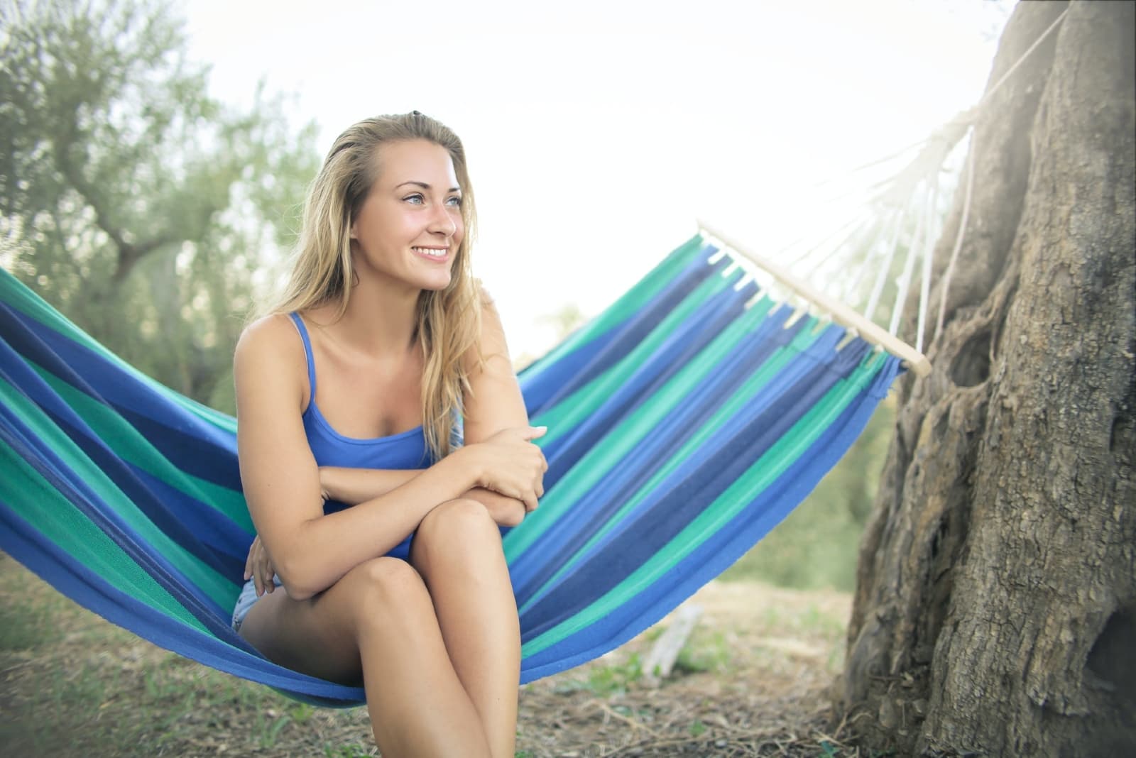 happy woman in blue top sitting on hammock