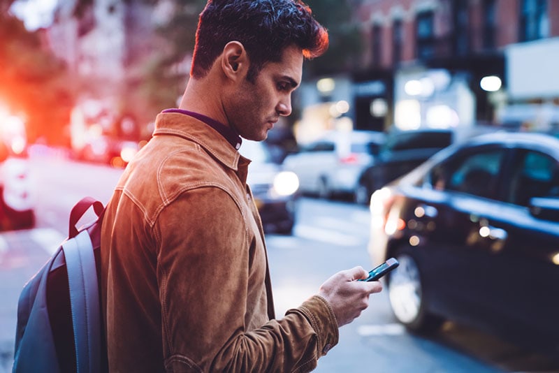 young man texting on the street