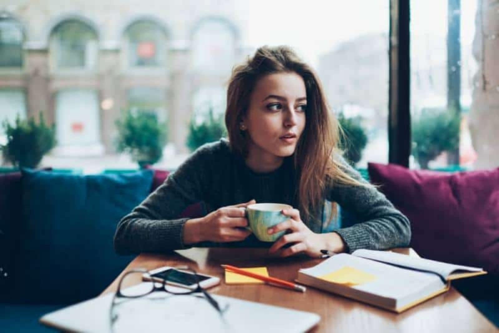 a woman sitting at a table drinking coffee