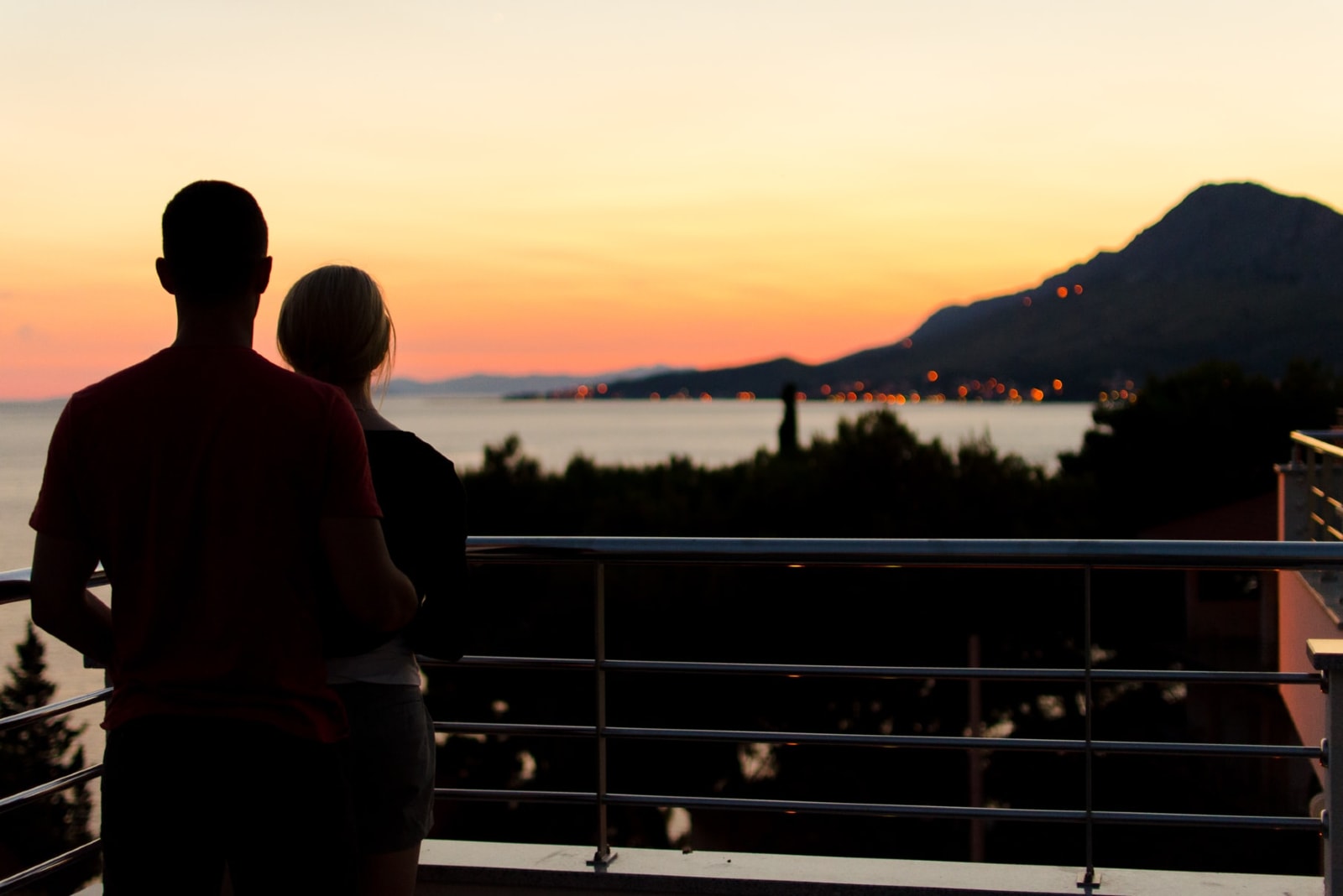 man and woman hugging while standing on balcony